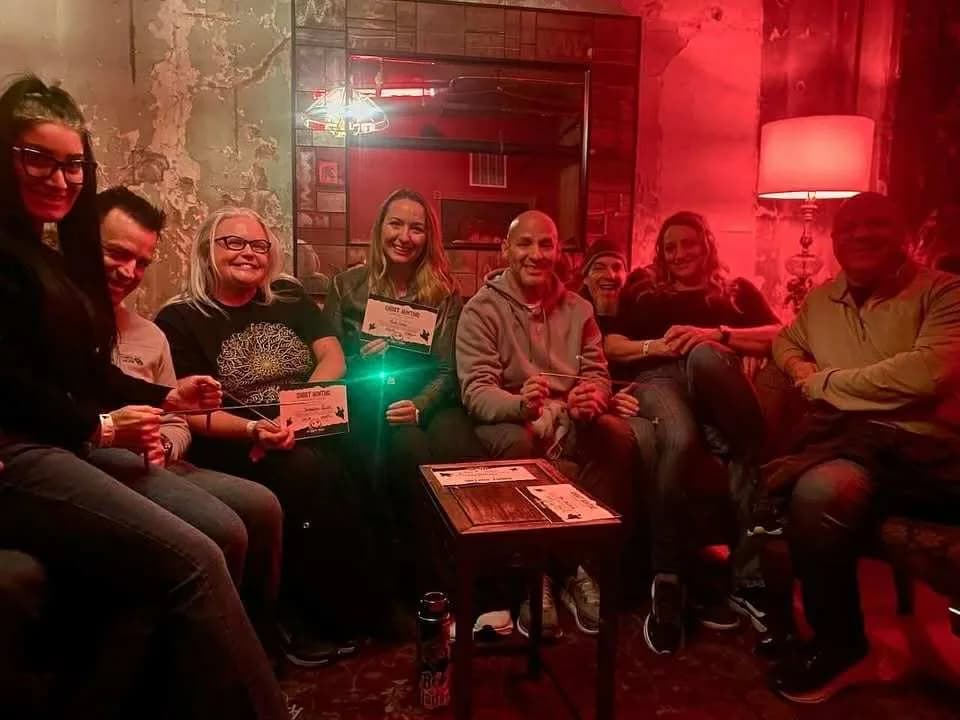 Participantes de Spooks & Spirits con equipo de caza de fantasmas en una sala con luz roja